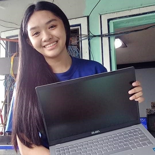 Wish kid Roxanne smiles for the camera holding her new laptop from Abensons